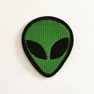May include: Green alien face embroidered patch with black eyes.
