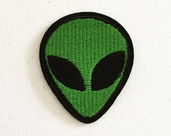 May include: Green alien face embroidered patch with black eyes.