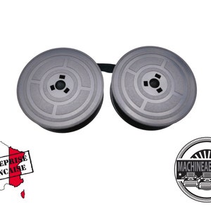 Peut inclure: Deux bobines de ruban de machine à écrire noires, chacune avec un trou central et des cercles concentriques. Les bobines sont reliées par un ruban noir.