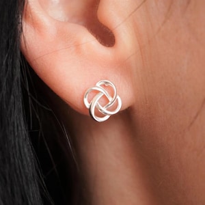 May include: Silver stud earrings with a knot design.