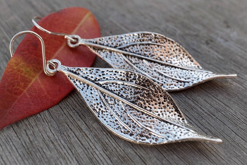 May include: A pair of silver leaf-shaped earrings with a textured surface.