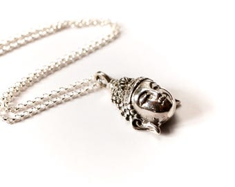 May include: A silver chain necklace with a pendant featuring a detailed silver Buddha head.