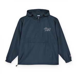 May include: A dark teal anorak jacket with a hood and a half-zip closure. The jacket features a front pocket and the text "dEfaid" in white script on the chest. A small Champion logo is visible on the left sleeve.