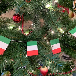 May include: A Christmas tree decorated with a string of Italian flags. The flags are green, white, and red.
