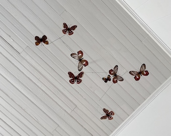 May include: A white ceiling with a mobile of red and brown butterflies hanging from it.