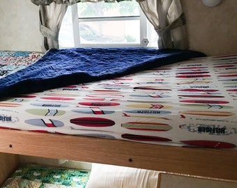 May include: A bunk bed with a blue blanket on top and a white and red patterned sheet with the word "Hilfiger" on it.