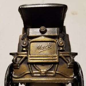 Peut inclure: Mod&egrave;le de voiture ancienne de couleur bronze avec le mot "Mack" en &eacute;criture sur le devant. La voiture a des roues noires et un toit noir. Le mod&egrave;le est une r&eacute;plique d&eacute;taill&eacute;e d'un v&eacute;hicule vintage.