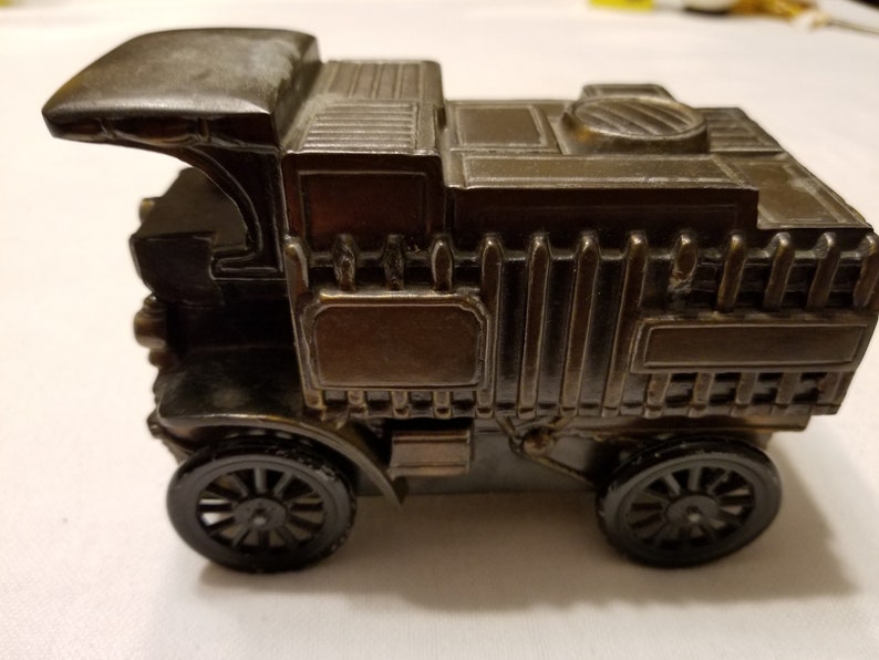 Peut inclure: Un taille-crayon d&eacute;taill&eacute; de style antique en forme de camion vintage. Le taille-crayon de couleur bronze fonc&eacute; pr&eacute;sente des d&eacute;tails complexes, notamment une cabine, une zone de chargement et des roues &agrave; rayons. Le design &eacute;voque la nostalgie et le savoir-faire.