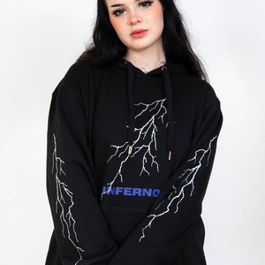 Puede incluir: Sudadera con capucha negra con un dise&ntilde;o de rayo blanco y la palabra "INFERNO" en letras azules.