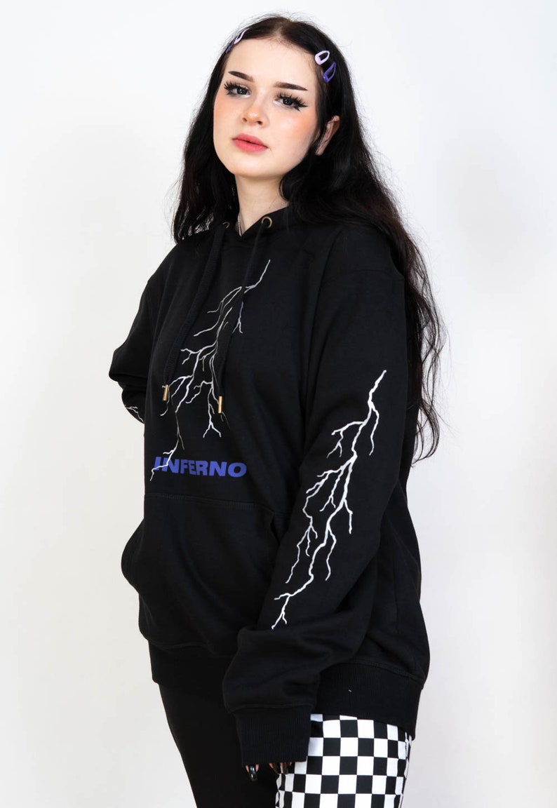 Puede incluir: Sudadera con capucha negra con un dise&ntilde;o de rayo blanco y la palabra "INFERNO" en letras azules en la parte delantera.