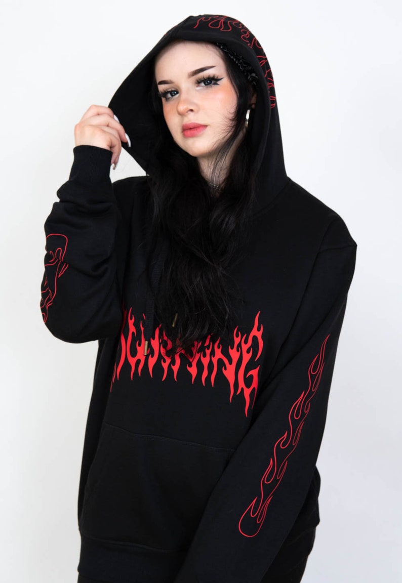 Puede incluir: Sudadera con capucha negra con un dise&ntilde;o de llamas rojas en la parte delantera y las mangas. El texto "BURNING" est&aacute; escrito en llamas rojas en la parte delantera de la sudadera.