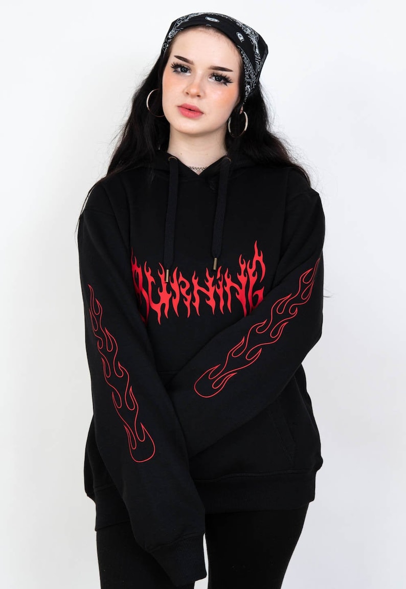 Puede incluir: Sudadera con capucha negra con un gr&aacute;fico rojo "BURNING" con llamas en la parte delantera y las mangas.