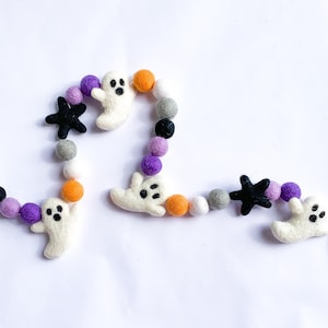 May include: A Halloween garland with white felt ghosts, black felt stars, and orange, purple, white, and gray felt balls.