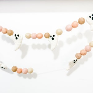 May include: A Halloween garland with white felt ghosts and brown and pink felt balls. The garland is strung on a clear thread.