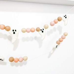 May include: A Halloween garland with white felt ghosts and brown and pink felt balls. The garland is strung on a white string.