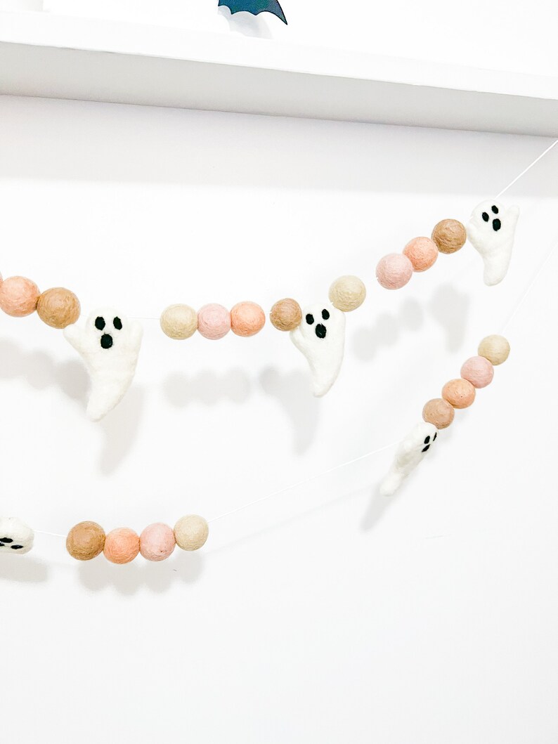 May include: A Halloween garland with white felt ghosts and brown and pink felt balls. The garland is strung on a white string.