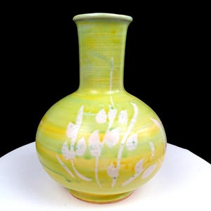 Puede incluir: Un jarrón de cerámica con cuerpo bulboso y cuello estrecho, con un esmalte brillante en tonos amarillo brillante y verde lima. La superficie está decorada con un patrón botánico blanco pintado a mano de hojas y tallos alrededor de la base.