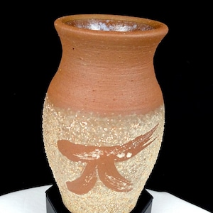 May include: A handcrafted, rustic pottery vase with a wide, textured base and a smooth, reddish-brown upper section. The vase features a brown brushstroke design on the lower half, adding an artistic touch to the ceramic piece.