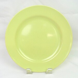 Puede incluir: Un plato circular de color amarillo claro sólido con un acabado liso y brillante y un borde ancho y plano. El plato presenta un diseño simple y limpio con un centro ligeramente hundido y un color uniforme en toda la superficie de la pieza.