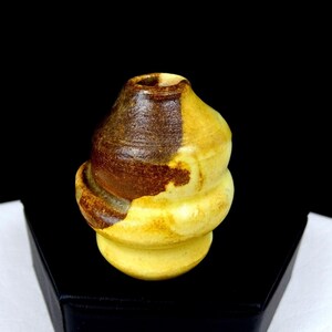 May include: A small, bulbous ceramic vase featuring a two-tone glaze. The upper portion is finished in a deep, textured dark brown, while the lower section and base are a smooth, vibrant yellow. The vessel has a narrow opening at the top.
