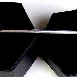 Peut inclure: Une cuillère en argent avec un manche orné et un bol rond. La poignée présente un motif détaillé de volutes. La cuillère est présentée sur une surface noire.