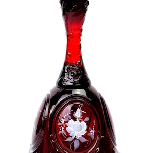 Puede incluir: Una campana de cristal rojo intenso con un mango alto y delgado con detalles florales en relieve. El cuerpo principal de la campana está decorado con un panel ovalado central que contiene un motivo floral blanco pintado a mano.