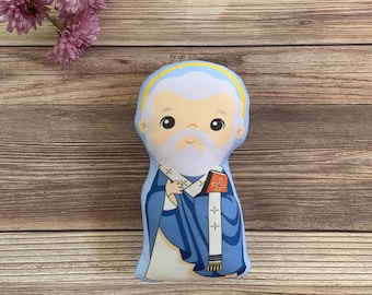 May include: A plush toy of a cartoon depiction of a religious figure wearing a blue and white robe with a yellow halo. The figure has a white beard and is holding a book.