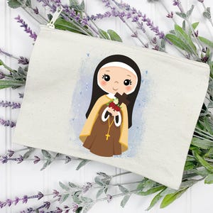 May include: A white canvas zippered pouch with a colorful illustration of a young girl in a brown habit holding a bouquet of flowers and a cross. The background is a light blue watercolor wash with white dots.