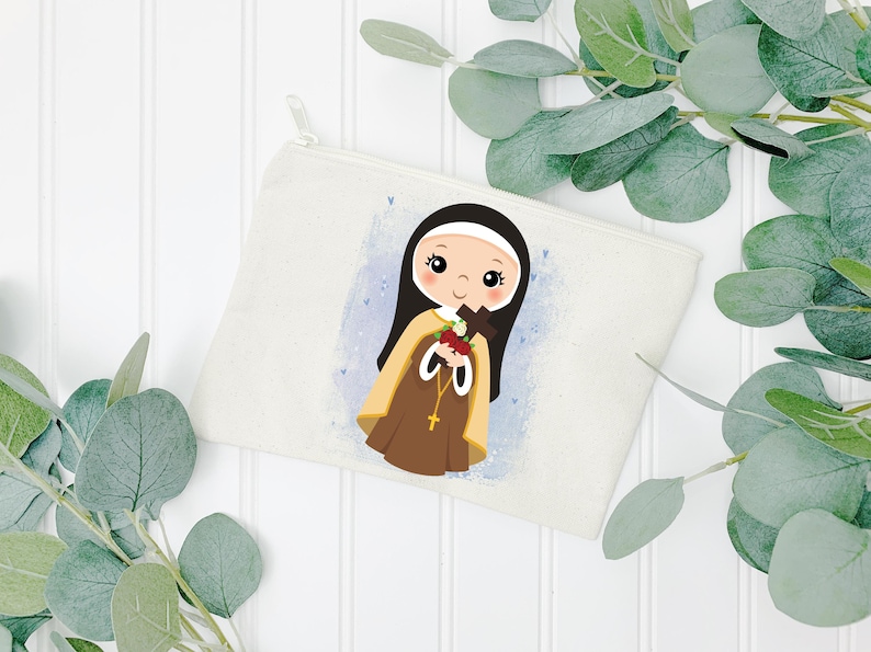 May include: A white canvas zippered pouch with a colorful illustration of a young girl in a brown and white habit holding a cross and flowers. The girl has brown hair and blue eyes. The background is a light blue with white dots.