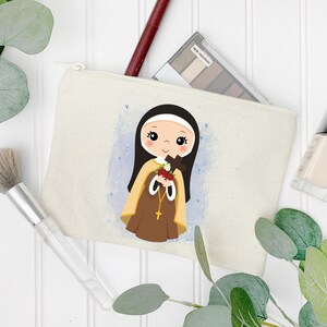 May include: A white canvas makeup bag with a cartoon illustration of a young girl in a brown habit holding a cross and a bouquet of red roses. The background is a light blue watercolor wash with white hearts.