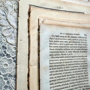 K&ouml;nnte beinhalten: Nahaufnahme von alten Buchseiten mit sichtbarem Text und unbeschnittenen Kanten. Die Seiten sind gestapelt und zeigen den Text einer Dissertation. Das Papier hat einen warmen, gealterten Ton, und der Text ist in schwarzer Tinte. Die Seiten sind leicht zerrissen und abgenutzt.
