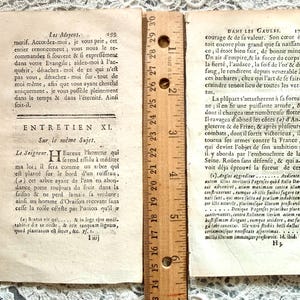 K&ouml;nnte beinhalten: Zwei Seiten aus einem antiken Buch mit franz&ouml;sischem Text, mit einem Lineal zur Ma&szlig;stabsbestimmung. Die Seiten sind gealtert mit sichtbarem Text und einem Lineal, das Messungen in Zentimetern anzeigt. Das Buch scheint ein historisches Dokument zu sein.