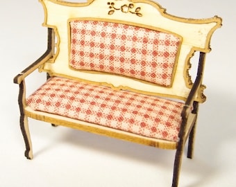 May include: A miniature wooden bench with a red and white checkered fabric cushion. The bench has a carved floral design on the back.