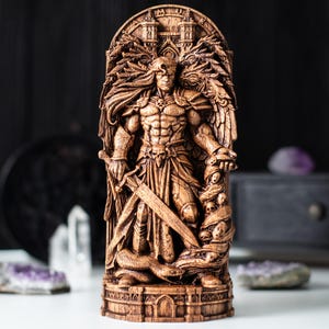 Pode incluir: Escultura de madeira detalhada de uma figura de guerreiro com espada e cobra. A figura tem uma constituição muscular, asas e é adornada com crânios. A escultura é esculpida em tons de castanho e assenta numa base decorativa.