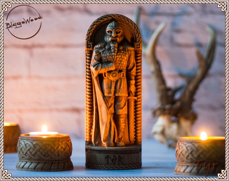 May include: A wooden carving of a Viking warrior with a beard and helmet, standing in a carved wooden frame. The carving is on a wooden base with the rune "Tyr" carved into it. The carving is lit by two candles in wooden candle holders.