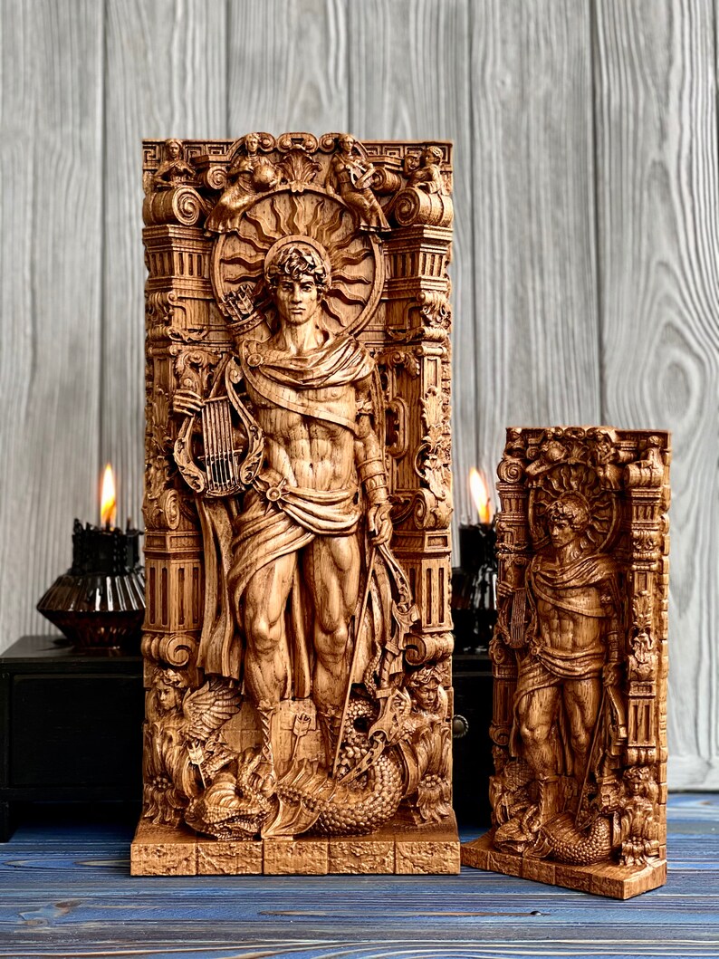May include: Two wooden carvings of a male figure standing in a decorative frame. The figure is holding a lyre and a staff. The carvings are detailed and intricate, with a sunburst design above the figure's head. The carvings are on a wooden base.