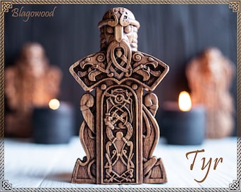May include: A wooden carving of the Norse god Tyr, depicted with a horned helmet and holding a sword. The carving is intricately detailed with knotwork and other Norse symbols. The word "Tyr" is written in brown text below the carving.