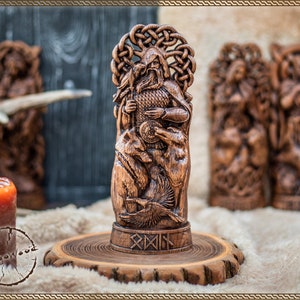 May include: A detailed wooden carving of a figure with a beard, holding a shield and surrounded by animals and a bird. The carving is on a wooden base with runes. Other wooden carvings and candles are in the background.