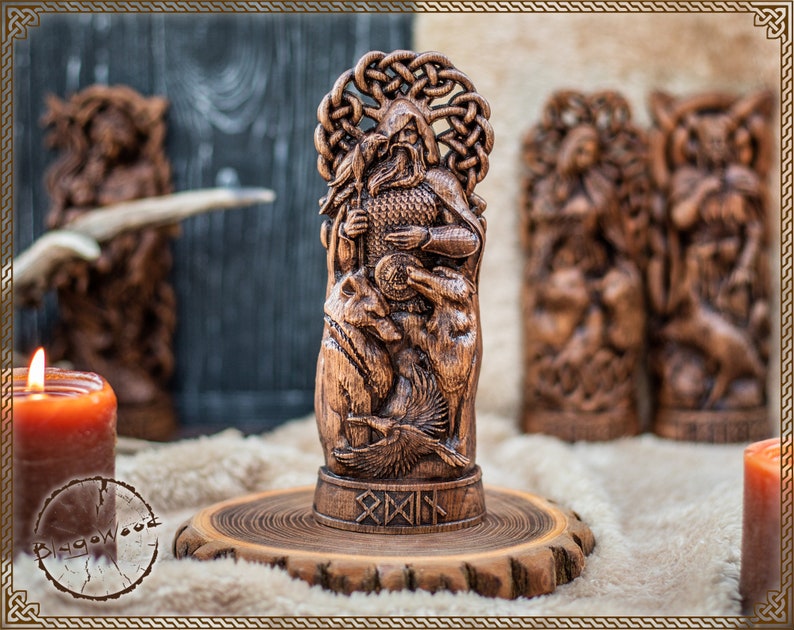 May include: A detailed wooden carving of a figure with a beard, holding a shield and surrounded by animals and a bird. The carving is on a wooden base with runes. Other wooden carvings and candles are in the background.
