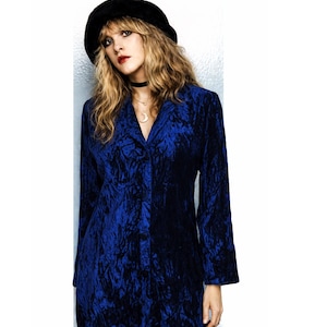 May include: A white ceramic mug with a black handle and the text "But First, Coffee" in a bold, black font. The mug is on a wooden surface. The mug is approximately 10 cm tall.