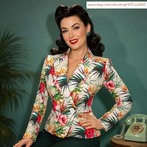 May include: A double-breasted blazer with a vibrant floral print featuring red, yellow, and green tropical flowers and leaves on a white background. The blazer has long sleeves and a tailored fit, perfect for a stylish look. The website address is visible at the top.