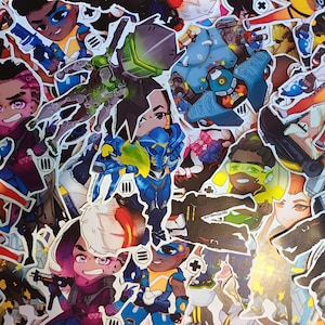 May include: A collection of colorful stickers featuring various cartoon characters in action poses. The stickers showcase a variety of designs, with a mix of vibrant colors and detailed illustrations. The stickers are likely for fans of video games.