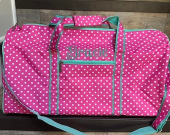 May include: Pink polka dot duffel bag with a teal zipper and trim. The bag has a teal strap and the name "Gracie" is embroidered on the front.