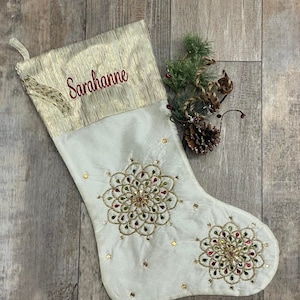 May include: A white Christmas stocking with gold and red embellishments. The stocking has a gold top with the name "Sarahanne" embroidered in red.