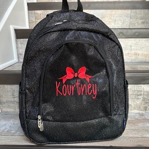 May include: Black glitter backpack with a red bow and the name Kourtney embroidered on the front.