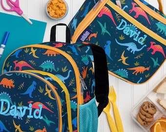 May include: A dark blue backpack and a matching lunch bag, both featuring a colorful dinosaur pattern and the name David embroidered in light blue. The backpack has a mesh side pocket, and the lunch bag includes a yellow zipper and handle.