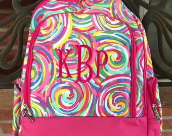 May include: A colorful backpack with a swirl pattern in shades of pink, yellow, blue, and green. The backpack has a solid pink bottom and trim, with a monogram in pink thread. Features include zippered compartments and adjustable straps.