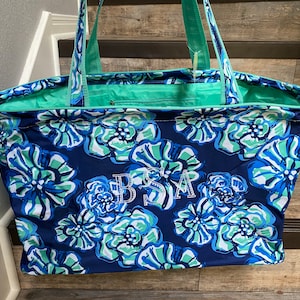 May include: A large blue and green floral tote bag with the initials "BSA" embroidered on the front.