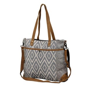May include: A gray and white geometric patterned tote bag with brown leather straps and accents. The bag has a top zipper closure and a detachable shoulder strap.