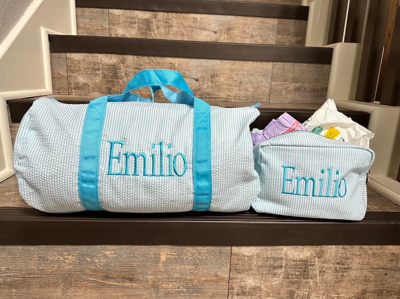 May include: Two blue and white striped travel bags with turquoise handles and the name "Emilio" embroidered on them.